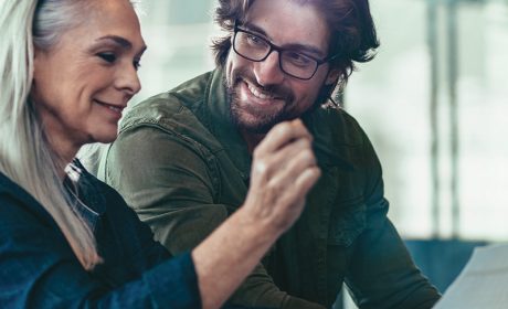 Two people smiling looking at a laptop