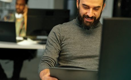 Person smiling at desk while looking at a tablet