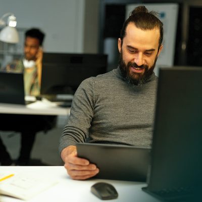 Person smiling at desk while looking at a tablet