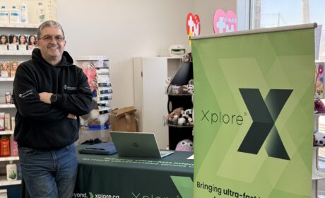 A photo of Todd from Authorized Xplore Dealer, Winsor Communications standing at his booth at a local vendor market. His setup features an Xplore branded table cloth and sign.