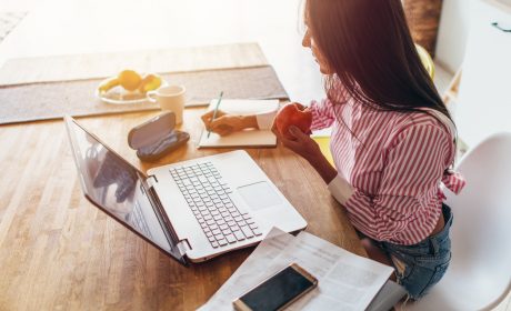 Woman making notes in front of a laptop