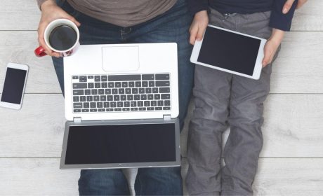 Adult sitting on the floor with young child browsing internet on laptop and tablet device scaled