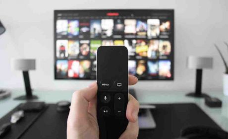 Person holding a remote to TV showing Netflix