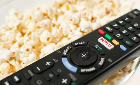 TV Remote sitting on top of a bowl of popcorn