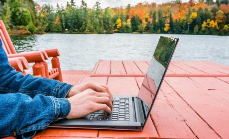 Person typing on a laptop outside by the lake