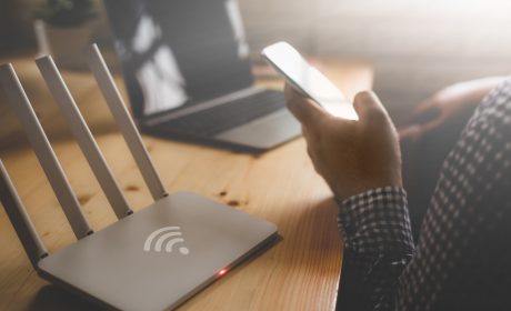 Person holding a cellphone sitting in front of a Wi-Fi modem