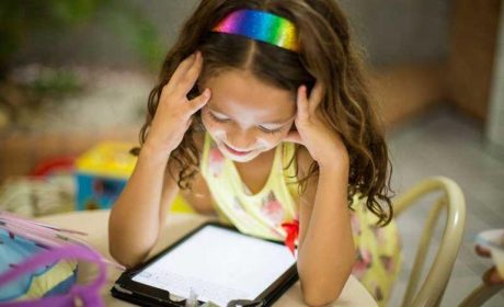 Girl sitting at a table playing on a tablet