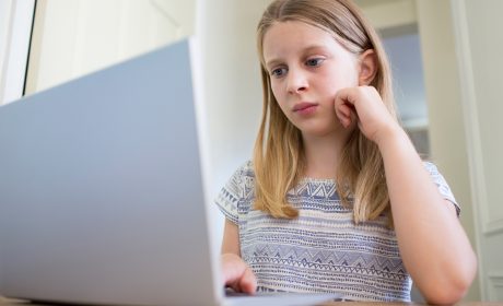 Girl sitting at a table using a laptop