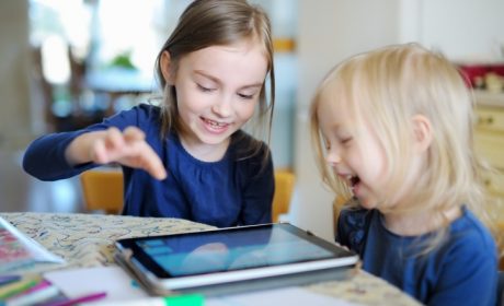 Two girls playing on a internet connected tablet at the table