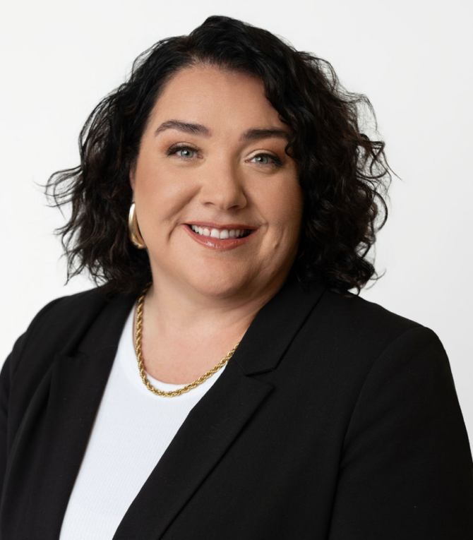 Xplore staff member Nicole posing for a headshot wearing a black blazer and white t-shirt.