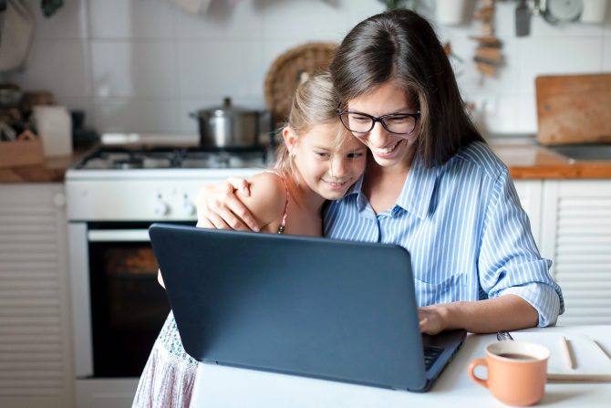 A mom and daughter happily using a laptop together