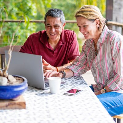 An older couple using a laptop on their balcony