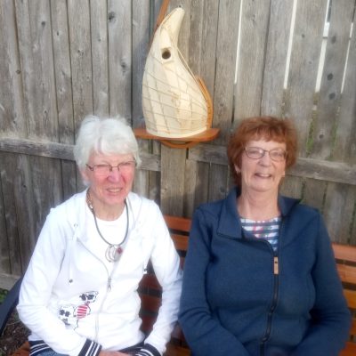 Two friends sitting with a birdhouse
