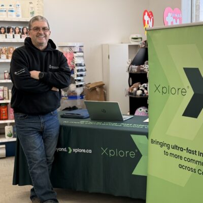 A photo of Todd from Authorized Xplore Dealer, Winsor Communications standing at his booth at a local vendor market. His setup features an Xplore branded table cloth and sign.