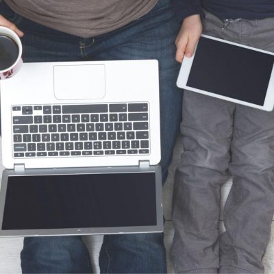 Adult sitting on the floor with young child browsing internet on laptop and tablet device scaled