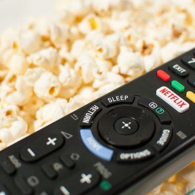 TV Remote sitting on top of a bowl of popcorn