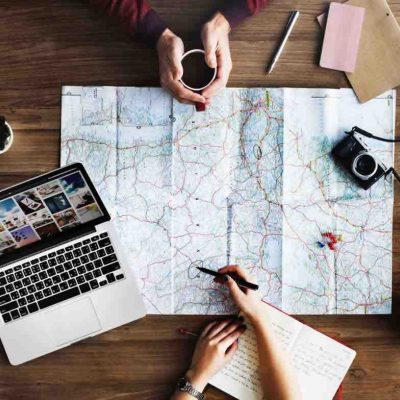 Friends using a map with a laptop to the side on a table