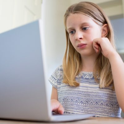 Girl sitting at a table using a laptop