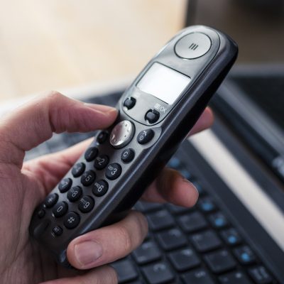 Un individu qui tient un téléphone résidentiel.