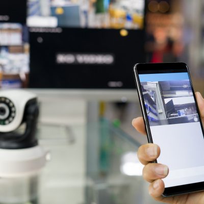 Person holding mobile phone near security system while using fast Internet