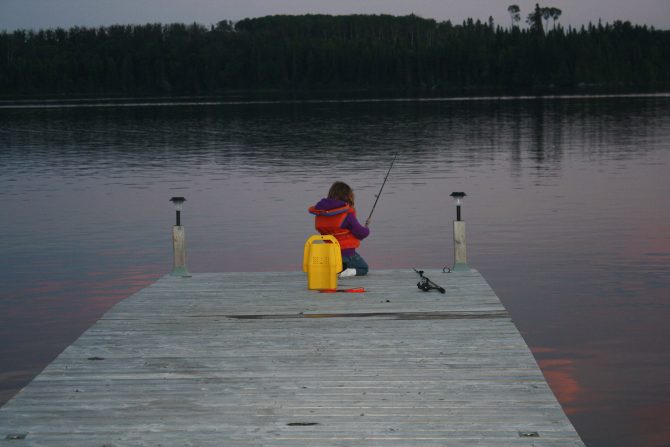 Photo of a young girl fishing off the end of a dock.
