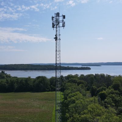A cell tower overlooking a landscape of trees and a body of water